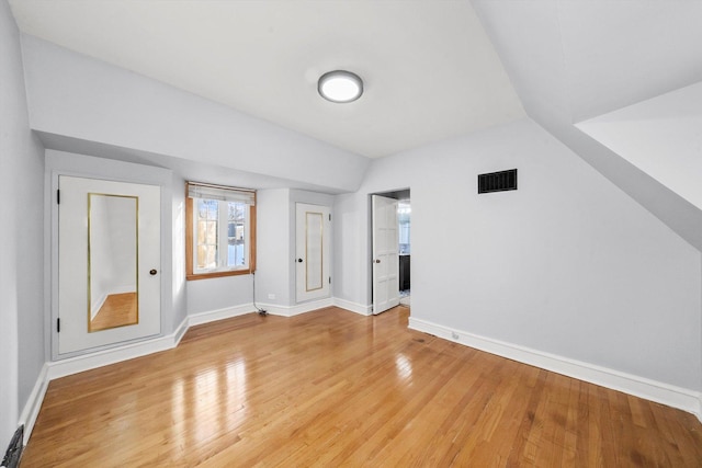 additional living space with lofted ceiling, visible vents, baseboards, and wood finished floors