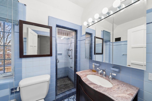 full bath with toilet, a shower stall, tile walls, and vanity