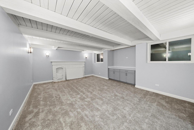 unfurnished room with light carpet, a brick fireplace, beam ceiling, and baseboards