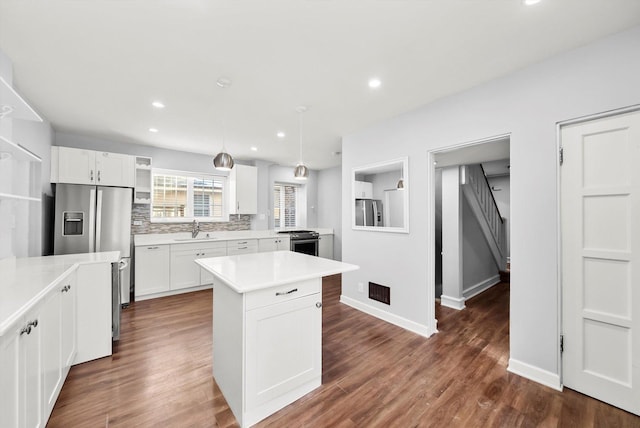 kitchen with light countertops, hanging light fixtures, a sink, and white cabinetry