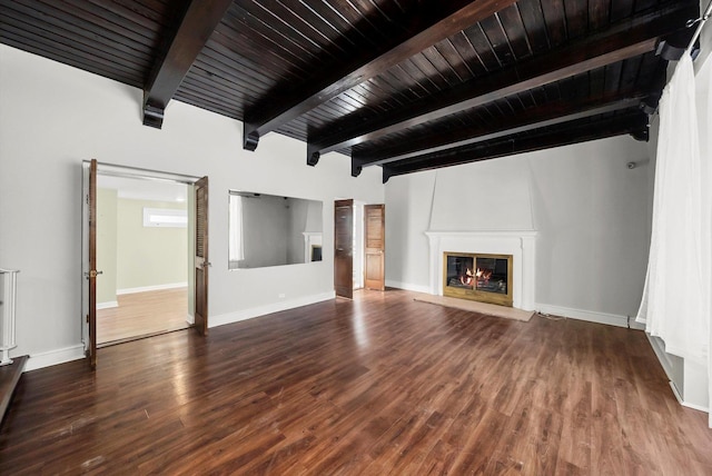 unfurnished living room with wood finished floors, a glass covered fireplace, beam ceiling, and baseboards