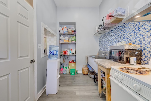 interior space with light countertops, white gas stove, backsplash, and light wood finished floors