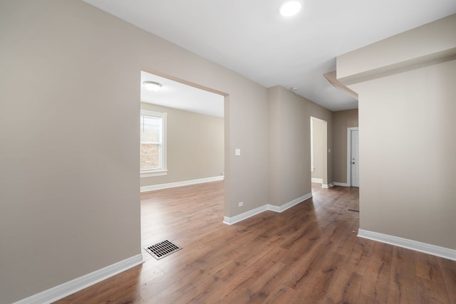 unfurnished room featuring wood finished floors, visible vents, and baseboards