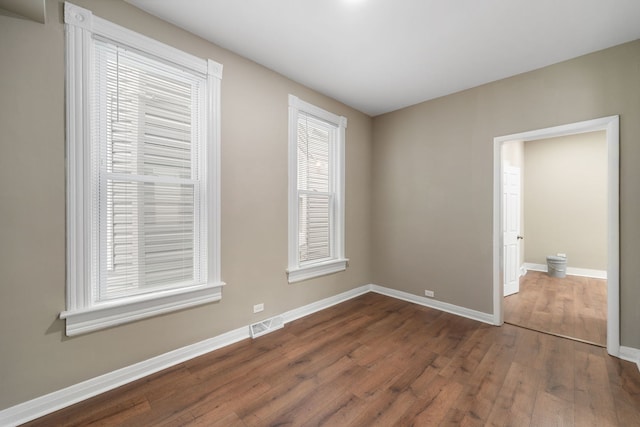 spare room featuring visible vents, dark wood finished floors, and baseboards