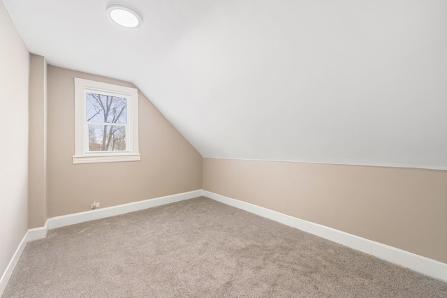 additional living space with lofted ceiling, light carpet, and baseboards