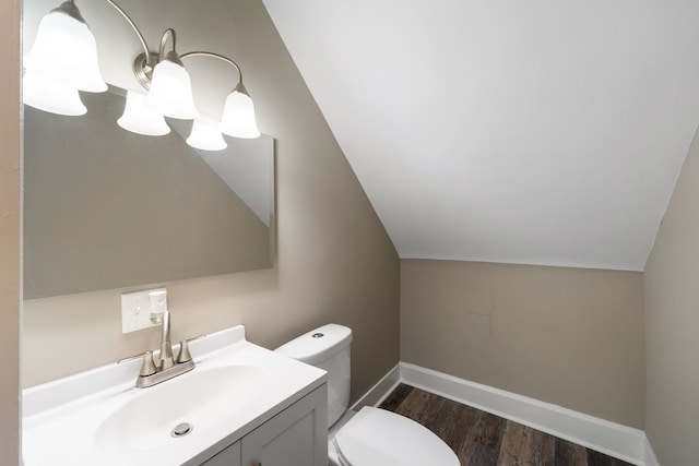 half bath featuring baseboards, toilet, wood finished floors, vaulted ceiling, and vanity