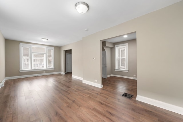 empty room featuring dark wood-style floors, baseboards, and visible vents