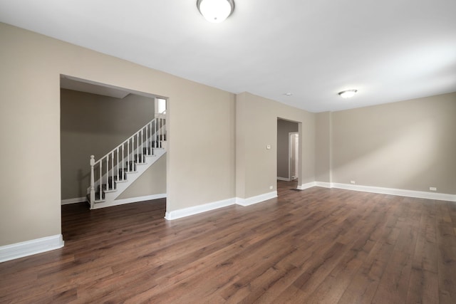 unfurnished room with stairs, dark wood-style floors, and baseboards