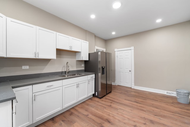 kitchen featuring recessed lighting, a sink, white cabinetry, stainless steel refrigerator with ice dispenser, and dark countertops