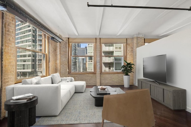 living room featuring beamed ceiling, brick wall, and wood finished floors