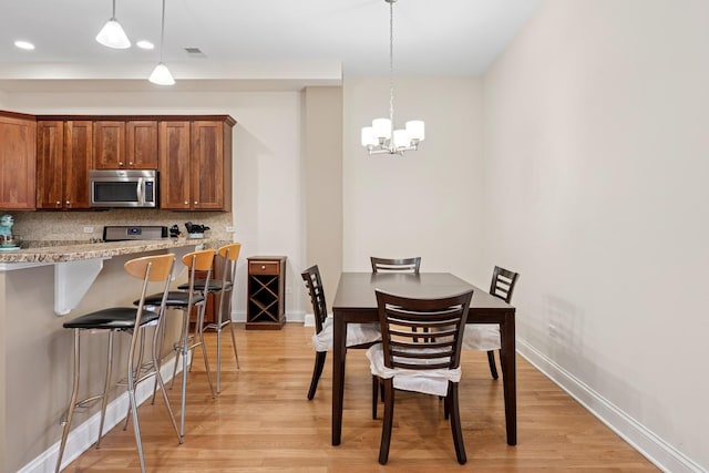 dining area featuring baseboards, a notable chandelier, visible vents, and light wood-style floors