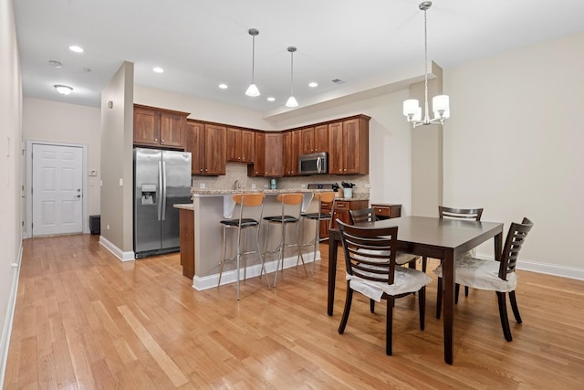 interior space featuring baseboards, recessed lighting, a notable chandelier, and light wood-style floors