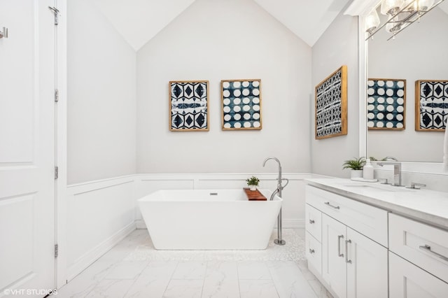 full bathroom with wainscoting, marble finish floor, vaulted ceiling, a freestanding bath, and vanity