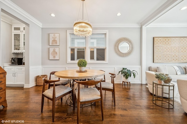 dining room featuring ornamental molding, dark wood-style flooring, a notable chandelier, and a decorative wall