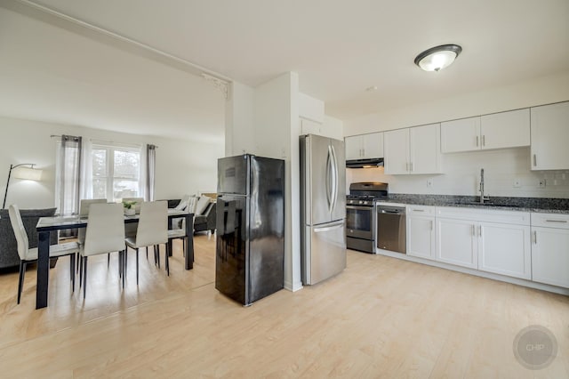 kitchen with stainless steel appliances, white cabinets, a sink, light wood-type flooring, and under cabinet range hood