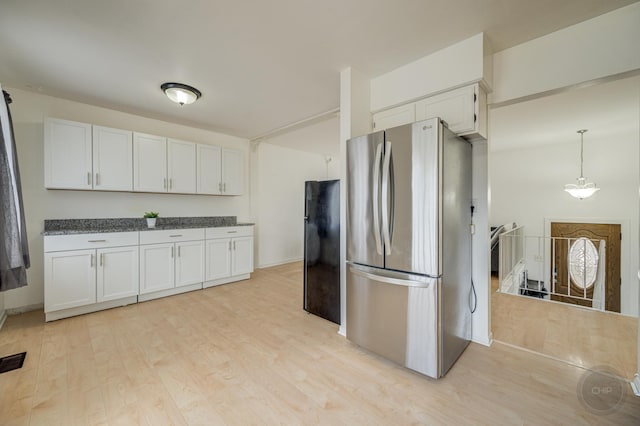 kitchen with visible vents, white cabinets, freestanding refrigerator, vaulted ceiling, and light wood-style floors