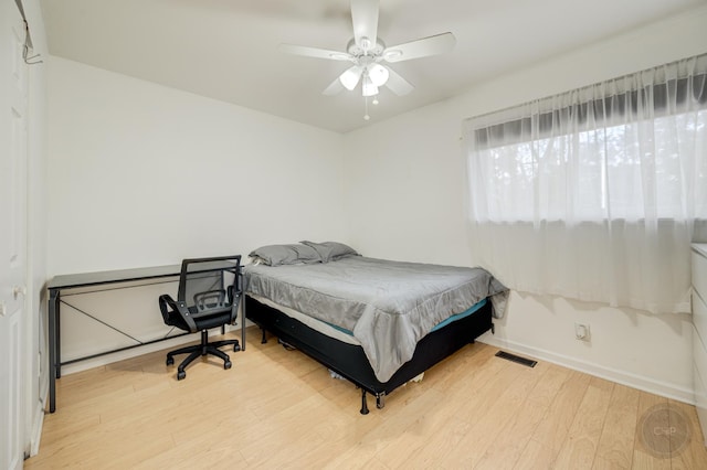 bedroom with ceiling fan, wood finished floors, visible vents, and baseboards