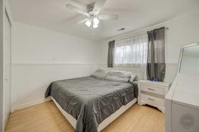 bedroom featuring light wood finished floors, baseboards, visible vents, and ceiling fan