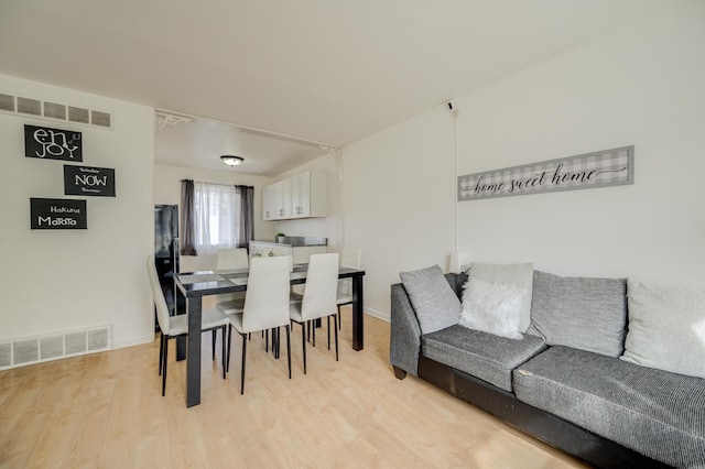 dining area with light wood-style flooring, visible vents, and baseboards