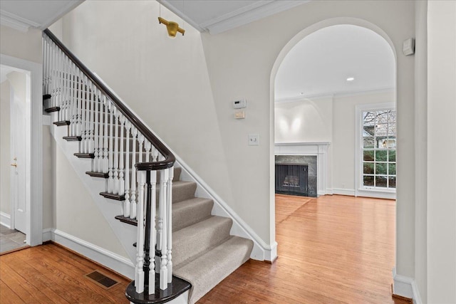 stairway with hardwood / wood-style flooring, visible vents, arched walkways, and ornamental molding