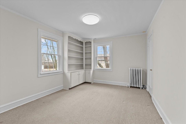 carpeted empty room featuring baseboards, a healthy amount of sunlight, crown molding, and radiator heating unit