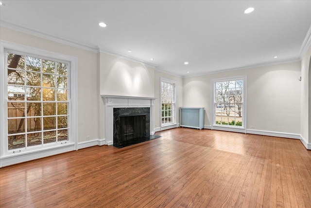 unfurnished living room with hardwood / wood-style flooring, baseboards, a premium fireplace, and ornamental molding