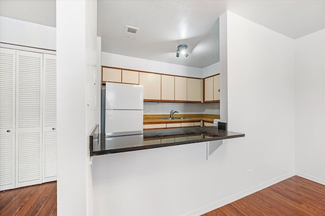 kitchen with cream cabinets, a sink, visible vents, freestanding refrigerator, and dark wood finished floors