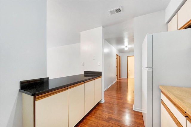 kitchen featuring visible vents, white cabinets, dark countertops, wood finished floors, and freestanding refrigerator