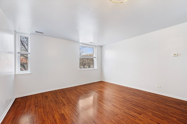 unfurnished room with wood finished floors, visible vents, and baseboards