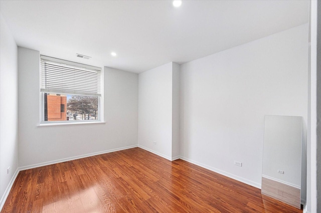 spare room with visible vents, baseboards, wood finished floors, and recessed lighting