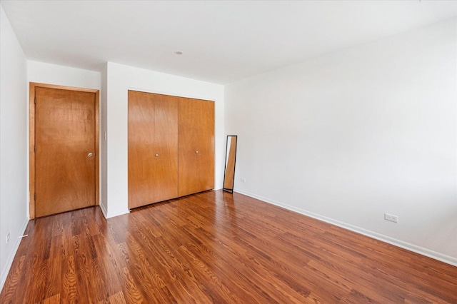 unfurnished bedroom featuring a closet, baseboards, and wood finished floors