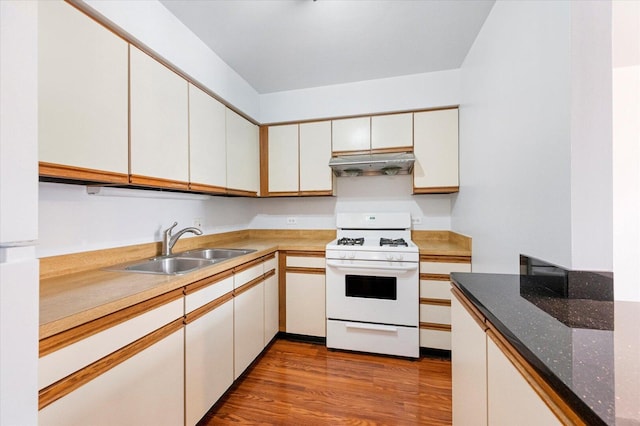 kitchen with white appliances, white cabinetry, a sink, and under cabinet range hood