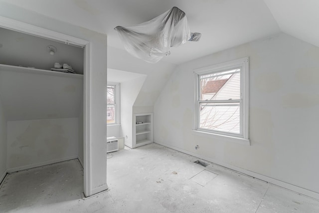 bonus room featuring lofted ceiling, built in shelves, and a wall unit AC