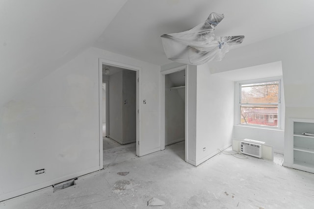 unfurnished bedroom featuring lofted ceiling, a closet, and an AC wall unit