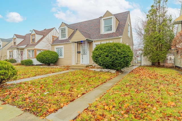 new england style home with a shingled roof, a gate, fence, and a front yard