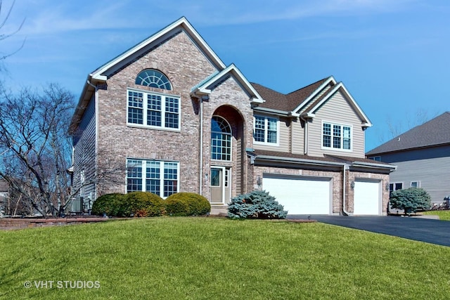 traditional-style house featuring aphalt driveway, brick siding, a garage, and a front lawn