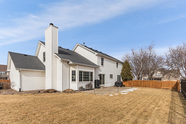 back of property with a lawn, a chimney, and a fenced backyard