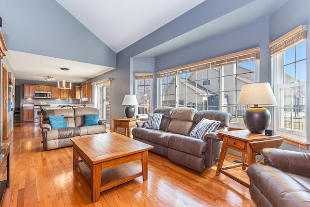 living room featuring high vaulted ceiling and light wood-style flooring