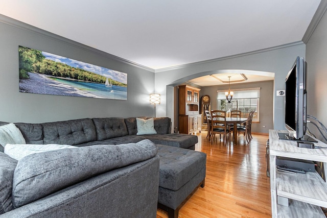 living room with arched walkways, crown molding, and wood finished floors