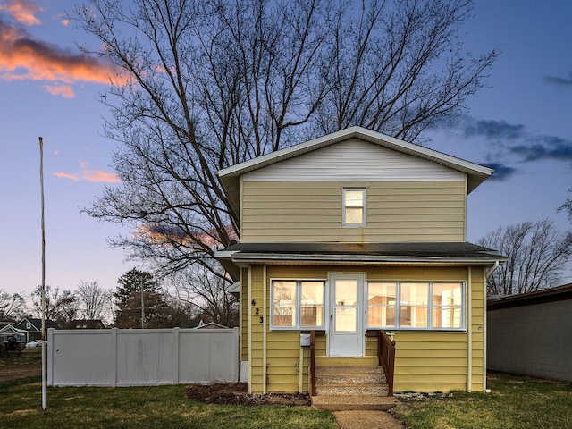 rear view of property featuring a yard, fence, and entry steps