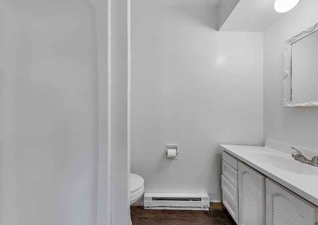 half bathroom with vanity, toilet, wood finished floors, and a baseboard heating unit