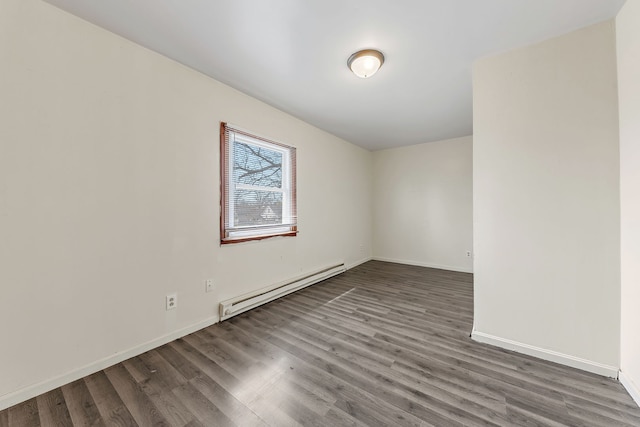 spare room featuring baseboards, baseboard heating, and wood finished floors