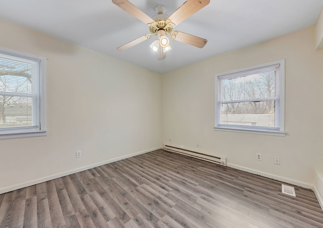 unfurnished room with wood finished floors, a baseboard heating unit, visible vents, a ceiling fan, and baseboards