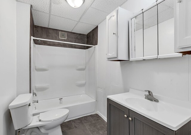full bathroom featuring toilet, a drop ceiling, vanity, and shower / tub combination