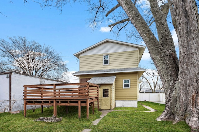 back of property with a yard, roof with shingles, a deck, and fence