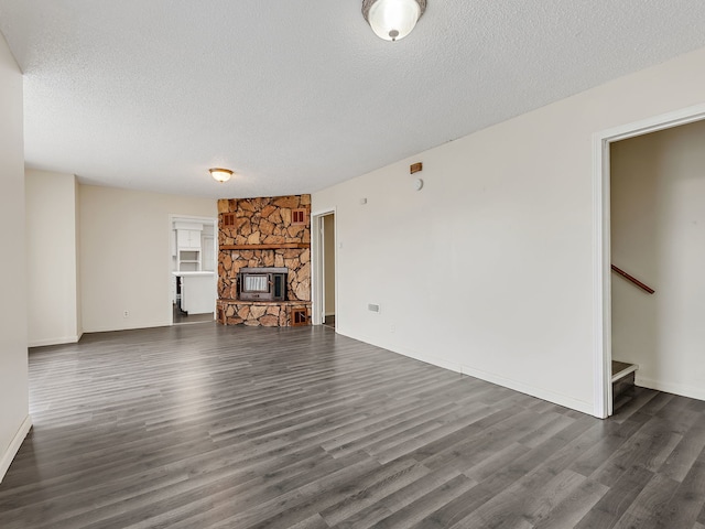 unfurnished living room with stairs, a textured ceiling, dark wood-style floors, baseboards, and a stone fireplace