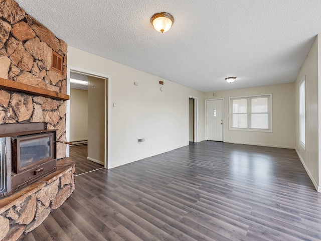 unfurnished living room featuring a textured ceiling, baseboards, dark wood-style floors, and visible vents