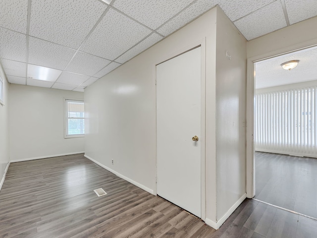 interior space featuring wood finished floors, baseboards, and a drop ceiling