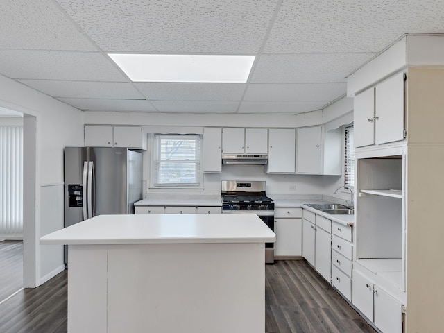 kitchen featuring a sink, stainless steel gas stove, under cabinet range hood, dark wood-style flooring, and a drop ceiling