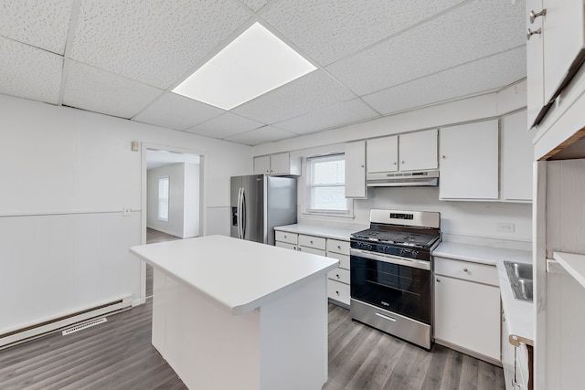 kitchen featuring wood finished floors, under cabinet range hood, light countertops, appliances with stainless steel finishes, and a baseboard radiator